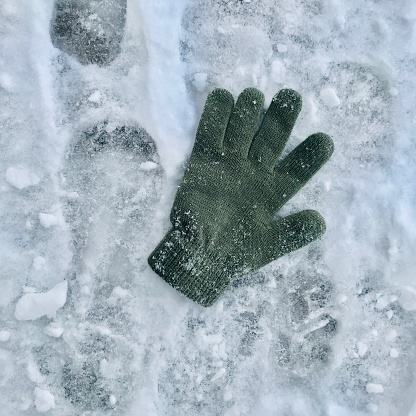Green glove laying in the snow.  iPhone