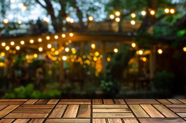 empty brown wooden floor or modern board, terrace with abstract night light bokeh of restaurant at night festival in garden, copy space for display product or object presentation, vintage color tone