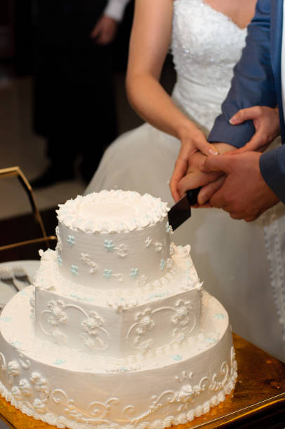 istock Newlyweds cut a beautiful white wedding cake. 1097484610