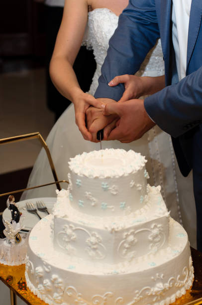 istock Newlyweds cut a beautiful white wedding cake. 1097484622
