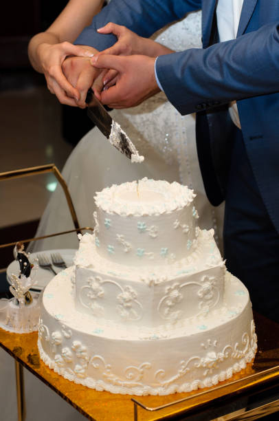 istock Newlyweds cut a beautiful white wedding cake. 1097484652