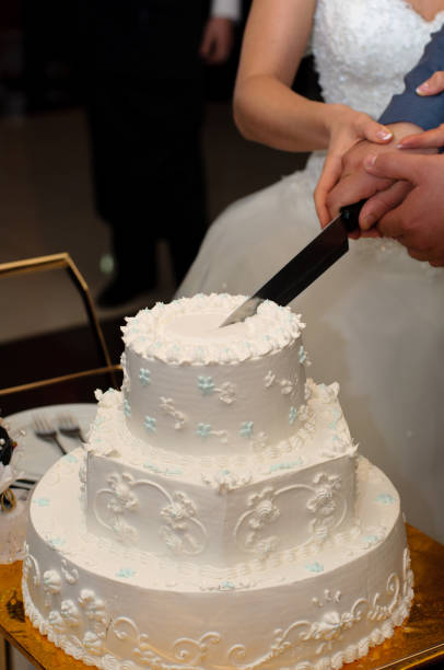 istock Newlyweds cut a beautiful white wedding cake. 1097484662
