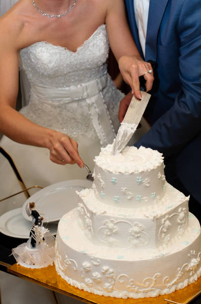 istock Newlyweds cut a beautiful white wedding cake. 1097484680