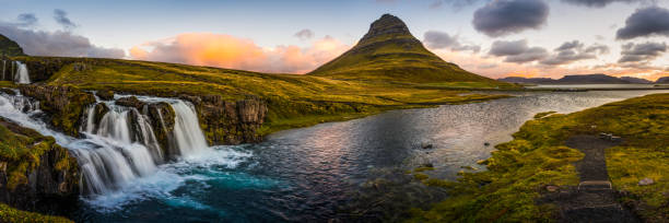 Iceland iconic waterfalls river Kirkjufell mountain peak panorama Vesturland sunrise The clear blue waters of Kirkjufellfoss waterfall tumbling down the mountainside to the ocean fjord beside Grundarfjordur beneath the iconic peak of Kirkjufell framed by the warm glow of sunrise over the Snaefellsnes peninsula in the far east of Iceland. kirkjufell stock pictures, royalty-free photos & images