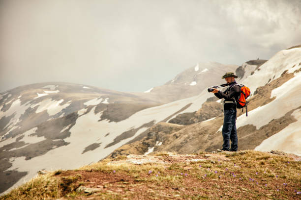 istock Young man taking photo on top of mountain while hiking 1097485132