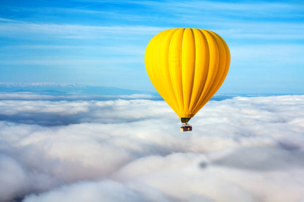 una mongolfiera gialla solitaria galleggia sopra le nuvole. concept leader, successo, solitudine, vittoria - hot air balloon landscape sunrise mountain foto e immagini stock