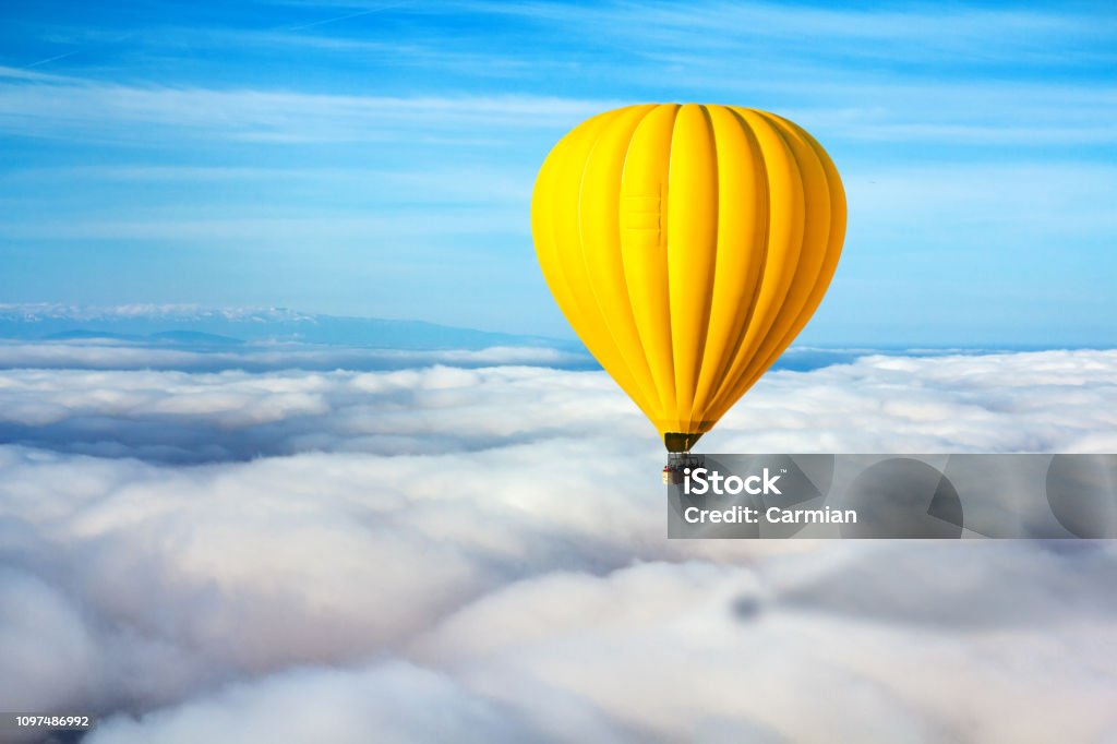 Одинокий желтый воздушный шар парит над облаками. Концепт-лидер, успех, одиночество, победа - Стоковые фото Воздушный шар роялти-фри
