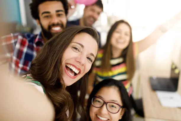 Photo of Happy friends talking a selfie in the office