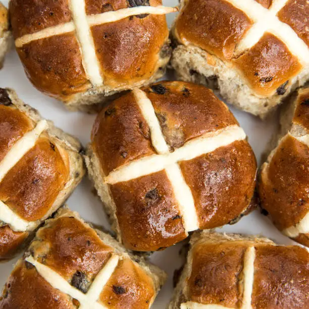 Looking down from above onto a seasonal food background of sticky and sweet Easter hot cross buns with copy space