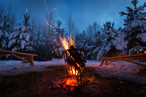 Bonfire in the winter forest illuminates the snow. Karelia, winter.