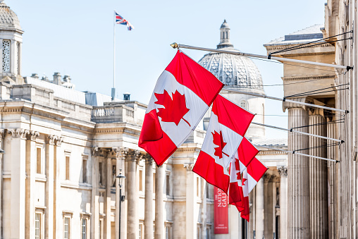 London, UK High Commission of Canada with closeup of row of red colorful Canadian flags on Cockspur Street in Westminster