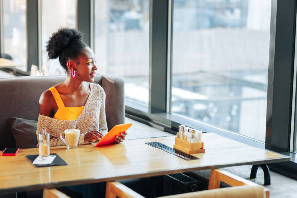 istock Curly dark-haired woman reading her electronic book in restaurant 1097506042
