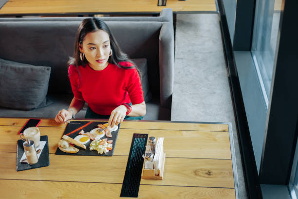 Dark-haired woman eating eggs and drinking coffee for breakfast