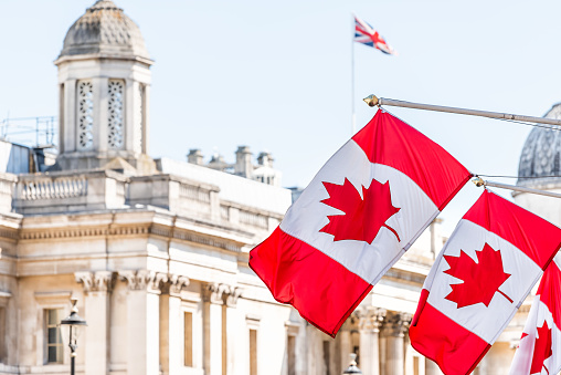 London, UK High Commission of Canada with closeup of row of red Canadian flags on Cockspur Street in Westminster