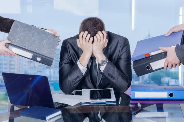 A businessman is closing his face with his hands in working stress assault.