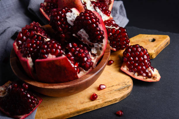 Ripe red pomegranate on wooden board and dark background. Close-up