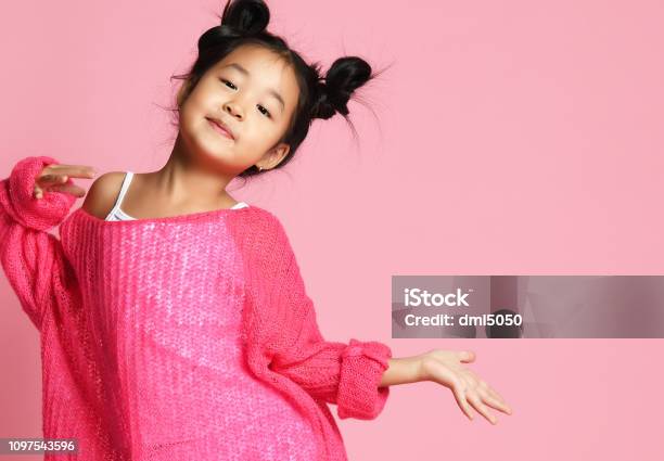 Asian Kid Girl In Pink Sweater White Pants And Funny Buns Is In Fashion  Pose And Smiles Free Text Space Stock Photo - Download Image Now - iStock