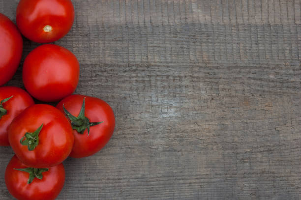 istock Several juicy red tomatoes on a wooden background. 1097550270