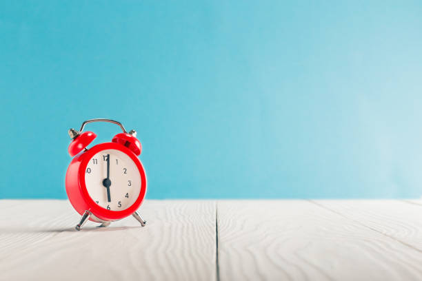 reloj de sobre mesa de luz de madera con colores de fondo. tiempo para despertar. - number 5 accuracy time blue fotografías e imágenes de stock