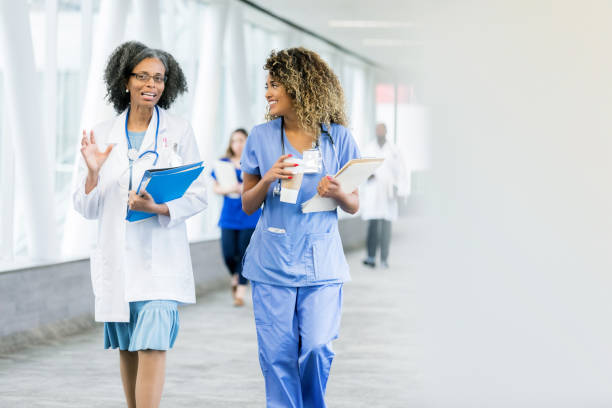 gli operatori sanitari camminano nel corridoio dell'ospedale - lab coat nurse doctor female doctor foto e immagini stock