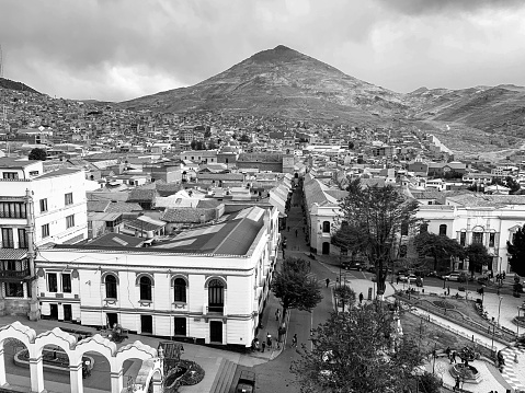 Potosi, Bolivia - December 21, 2018: High angle view of Potosi city from the bell tower of the Cathedral Basilica of Our Lady of Peace, with the 10 November Square in the historic center in the foreground, and the famous Cerro Rico (mountain) in the background (Bolivia). Potosi is one of the highest cities in the world at 4,090 meters, and sits at the foot of the Cerro de Potosí or Cerro Rico (rich mountain), named like this because of its huge amounts of silver that made the region the major supplier of silver for the Spanish Colonial Empire, and a very wealthy city with exquisite colonial churches and monasteries, administration buildings, schools and universities. For centuries, it was the location of the Spanish colonial mint (Casa de la Moneda), today a world-renowned museum. Silver is still extracted today. Potosi’s historic center is a UNESCO World Heritage Site.