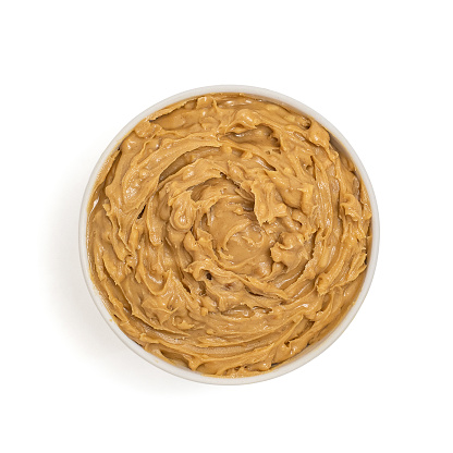 Peanut butter in bowl isolated on white background, top view.