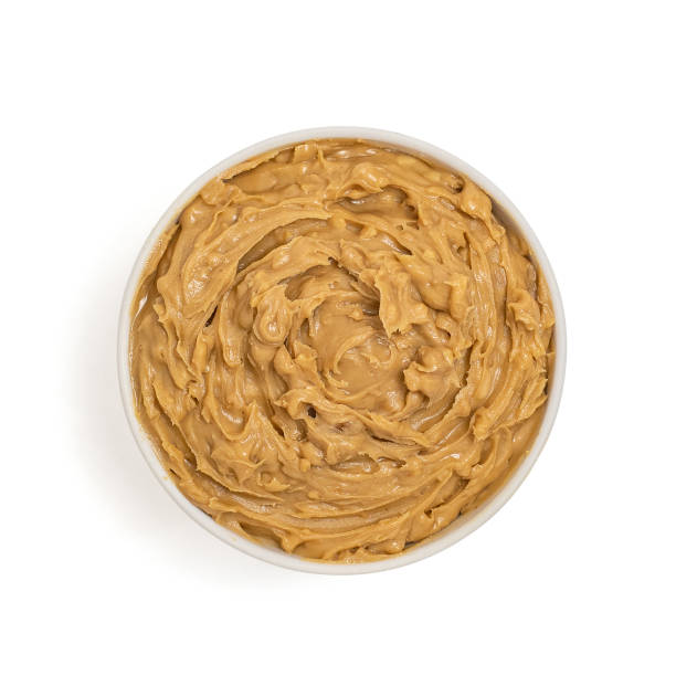Peanut butter in bowl isolated on white background, top view stock photo