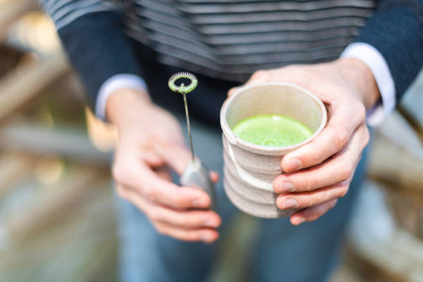 Man holding Japanese tea cup outside on backyard garden with whisk for matcha hot drink and foam Man holding Japanese tea cup outside on backyard garden with whisk for matcha hot drink and foam electric whisk stock pictures, royalty-free photos & images