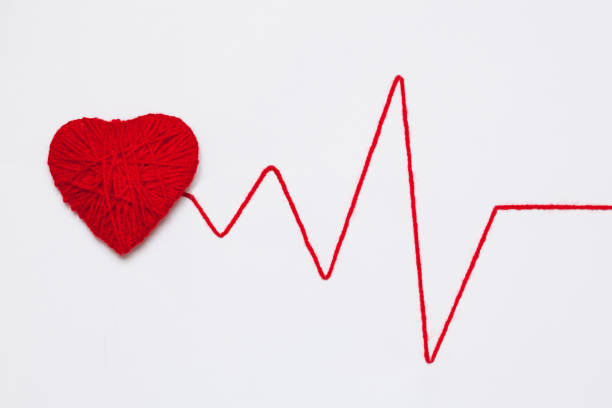 red yarn heart with thread like ECG pattern stock photo