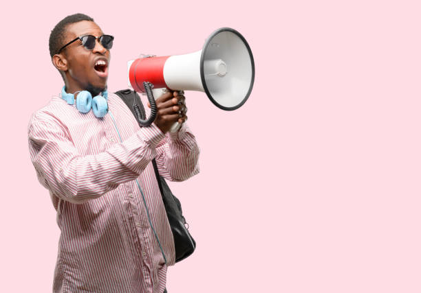 istock African black man student communicates shouting loud holding a megaphone, expressing success and positive concept, idea for marketing or sales 1097583918