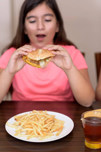 istock Young girl indoors eating a  burger 1097586336
