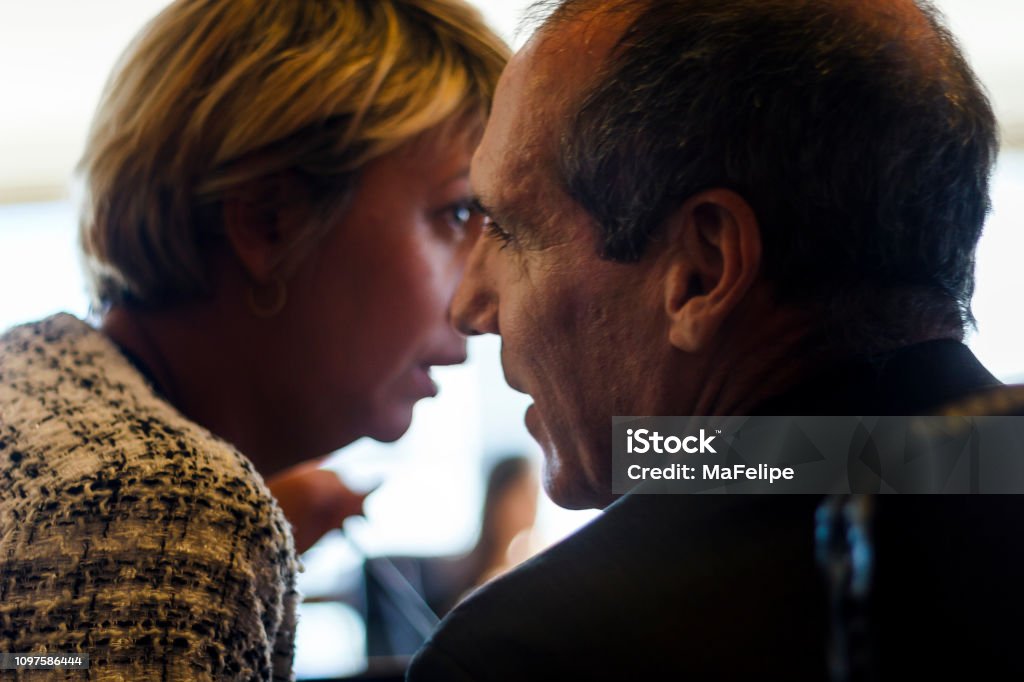 Businesswoman whispering to her colleague around a conference table Whispering Stock Photo