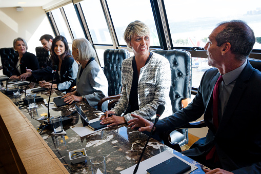 Group of businesswomen and businessman talking around a conference table.