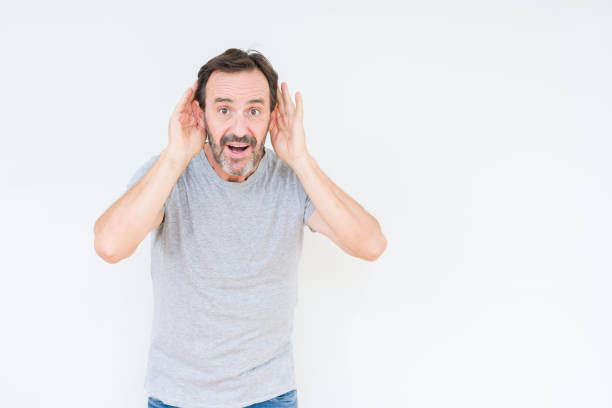 istock Handsome senior man over isolated background Trying to hear both hands on ear gesture, curious for gossip. Hearing problem, deaf 1097593158