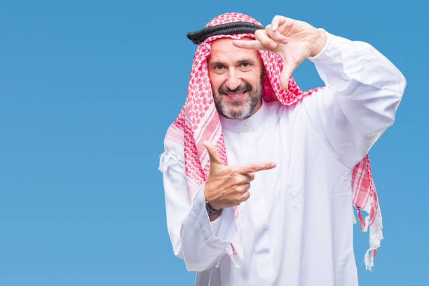 istock Senior arab man wearing keffiyeh over isolated background smiling making frame with hands and fingers with happy face. Creativity and photography concept. 1097598764