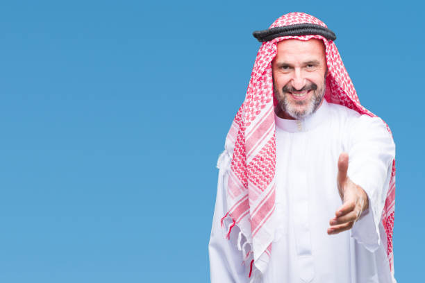 istock Senior arab man wearing keffiyeh over isolated background smiling friendly offering handshake as greeting and welcoming. Successful business. 1097598770