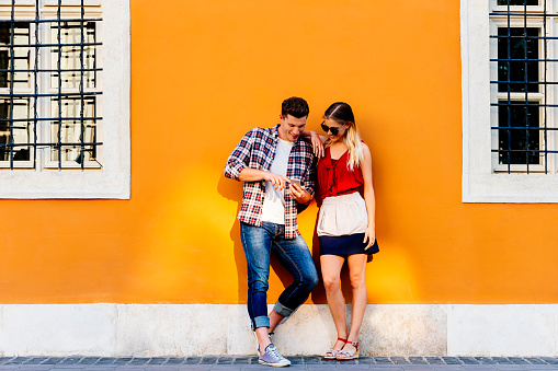 Portrait of young couple using mobile phone in the street. Mobile Concept.