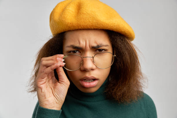 istock Angry dark haired woman has scrutinized look through spectacles, dissatisfied with something, poses over pink background, expresses negative emotions 1097604886