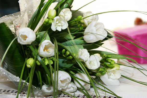istock Delicate bouquet with white tulips and green decorative grass on the table 1097627258