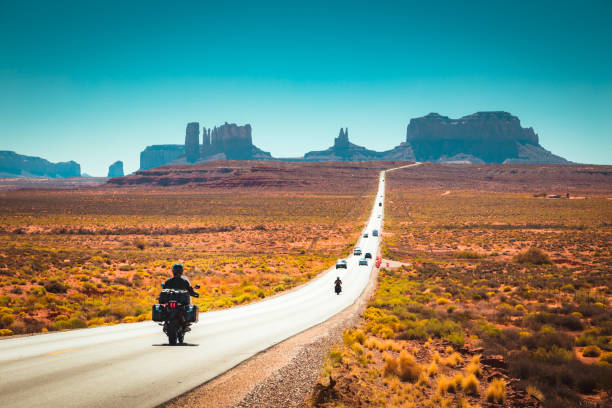 Biker on Monument Valley road at sunset, USA Classic panorama view of motorcyclist on historic U.S. Route 163 running through famous Monument Valley in beautiful golden evening light at sunset in summer, Utah, USA route 66 stock pictures, royalty-free photos & images