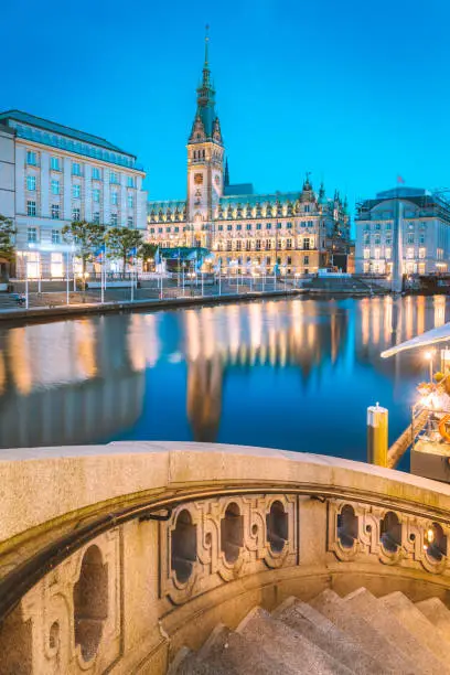 Classic twilight view of Hamburg city center with historic town hall reflecting in Binnenalster during blue hour at dusk, Germany