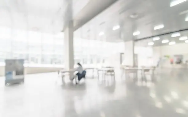 Photo of Office building or university lobby hall blur background with blurry school hallway corridor interior view toward empty corridor entrance, glass curtain wall, floor and exterior light illumination