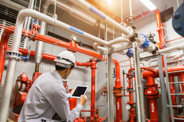 istock Engineer with tablet check red generator pump for water sprinkler piping and fire alarm control system. 1097682740