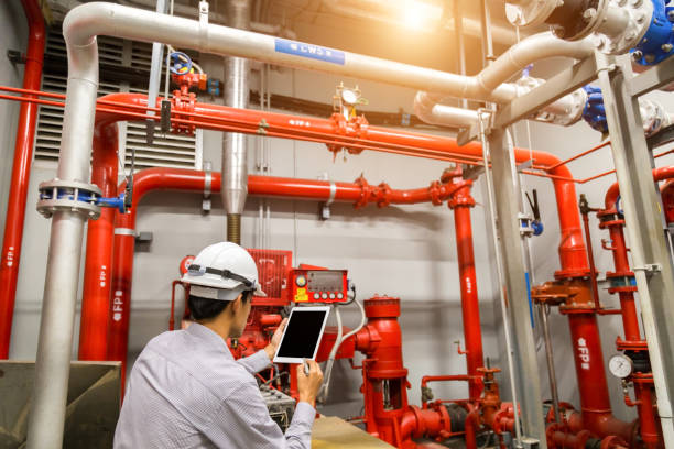 inżynier z tabletem sprawdzić czerwoną pompę generatora do rur zraszaczy wody i system kontroli alarmu pożarowego. - water system zdjęcia i obrazy z banku zdjęć