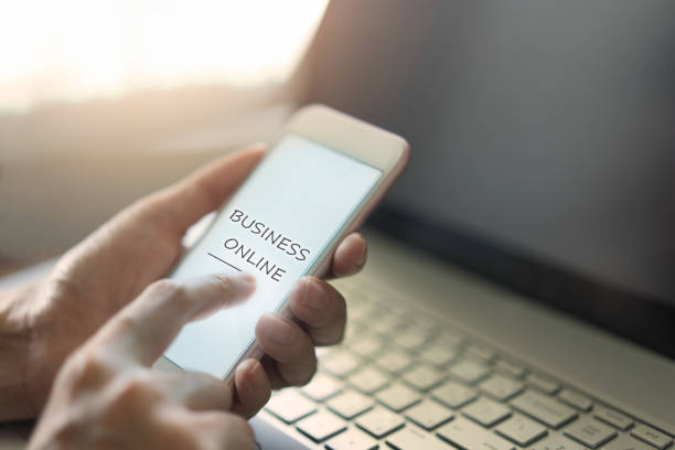 istock Hand using smartphone with laptop for business online 1097685564