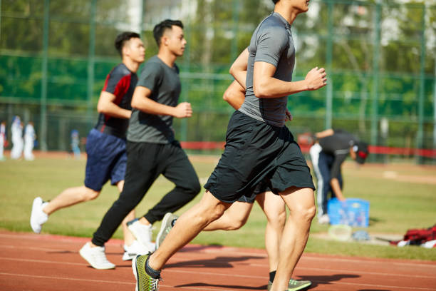 four young asian track and field athletes racing competing against each other.