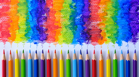 istock Vibrant rainbow colored water color coloring pencils or crayons in a row standing vertically with corresponding colorful shade drawing background, of the colors blending together, which features behind the crayons. 1097697454