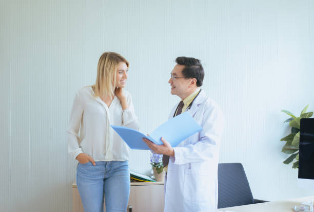 l’homme médecin examinant au patient femme heureuse et suivre un traitement à l’hôpital - general practitioner photos et images de collection