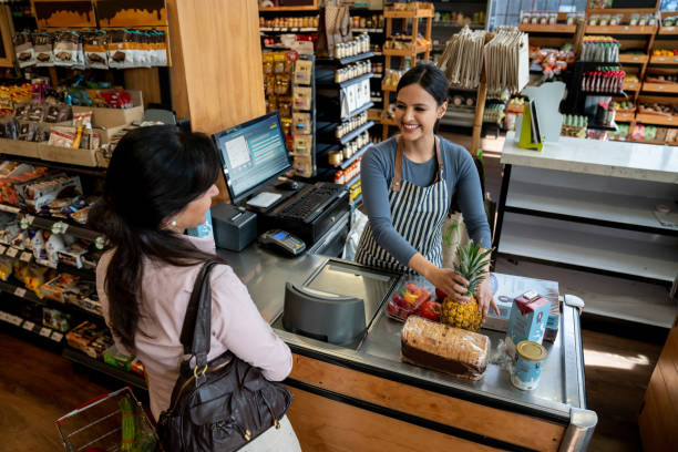 amigable cajero américa latina ayudando a cliente femenino si deseas pasar los productos por el lector de código de barras - checkout counter cash register retail supermarket fotografías e imágenes de stock