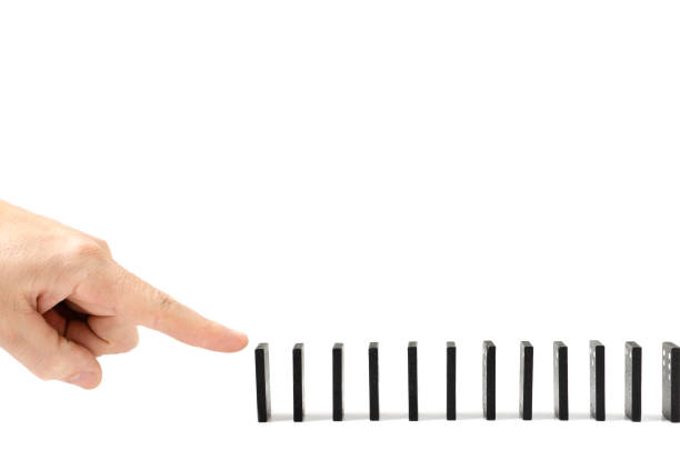 istock Finger, human hand drops the bones of dominoes on a white background. Fall, collapse, coercion, copy space. 1097715734